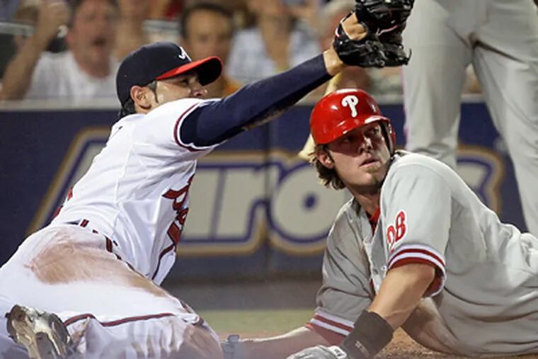 Atlanta Braves relief pitcher Mike Gonzalez, left, and Jayson Werth look for the umpire's call after Werth tried to score from third on a wild pitch in the eighth inning of the Phillies' 5-2 loss on Thursday. Werth was out on the play. (AP Photo/John Bazemore)