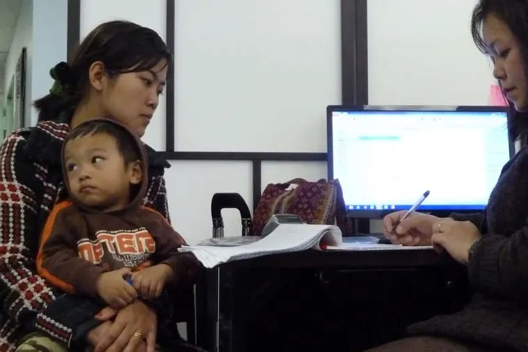 Biak Sung gets help from Zing Thluai (right), an outreach worker for Seamaac, a nonprofit organization in South Philadelphia. A lack of access to the Internet has hampered the group's clients.