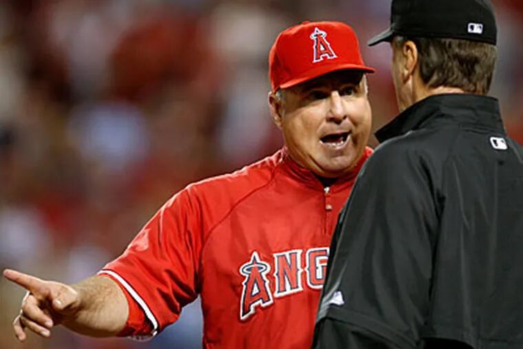 The Los Angeles Angels manager Mike Scioscia, left, talks with third base umpire Tim McClelland about a fifth inning double tag by Angels catcher Mike Napoli against New York Yankees Robinson Cano and Jorge Posada at Game 4 of the ALCS. Posada was called out and Cano remained on third as a fielder's choice. (AP Photo/Lenny Ignelzi)