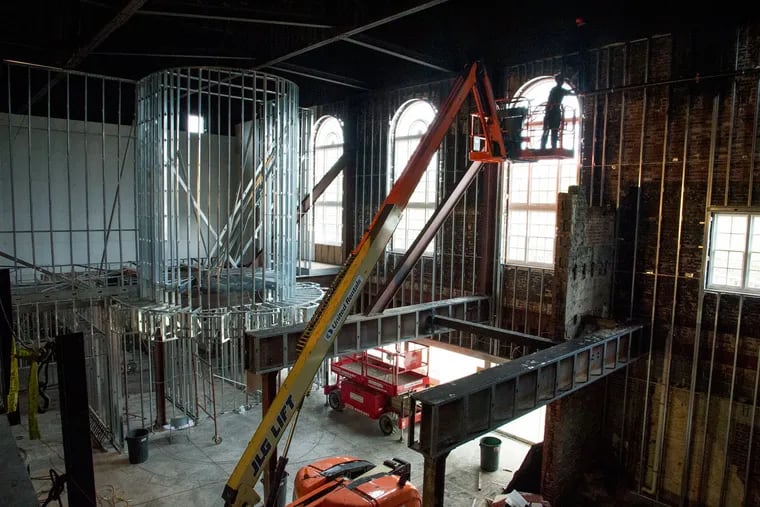 A worker high up on a lift works on the interior renovation of the historic Westmont Theater, which is being turned into a Planet Fitness.