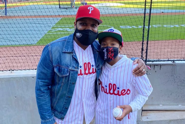 James Scott and his son, Josh, pose with a baseball signed by Phillies outfielder Bryce Harper and Braves first baseman Freddie Freeman. Josh Scott received the baseball after he went viral for giving away Freeman’s home run ball to a Braves fan.