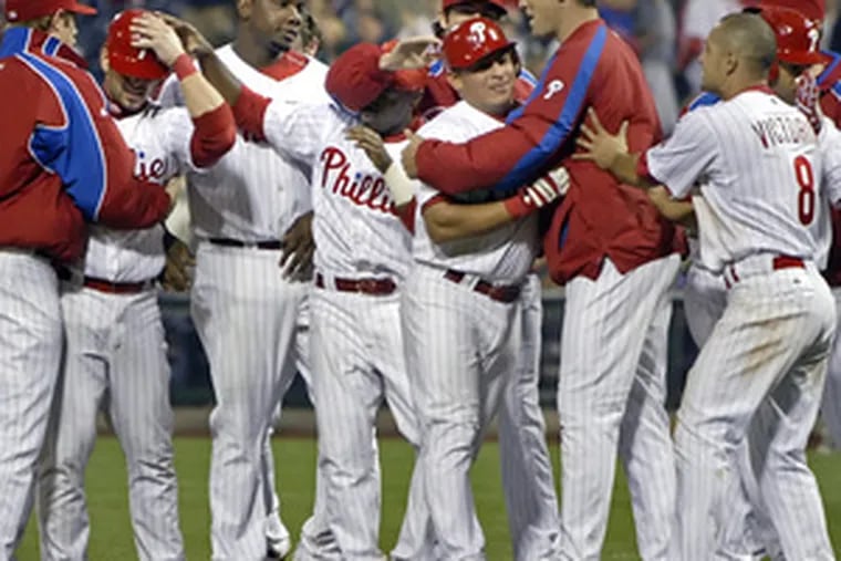 Teammates mob Carlos Ruiz (center) after his bases-loaded single wins it for Phils in ninth inning.
