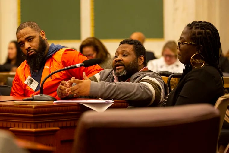Jaleel King, of Philadelphia, speaks in front of city council members during a special committee on gun violence in City Hall on Thursday, Feb. 20, 2020. King is accompanied by Jalil Frazier, left, and Victoria Wylie, Facilitator for a support group for paralyzed gunshot survivors, right, to bring awareness of the issues they face.