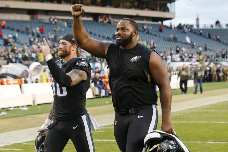 Eagles defensive tackle Fletcher Cox and defensive end Chris Long raise their arms after the victory Sunday.