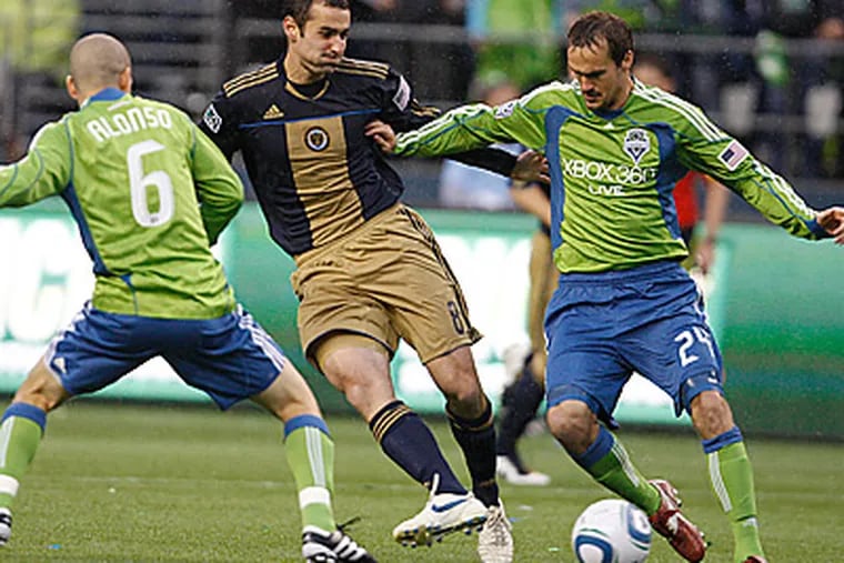 Union's Andrew Jacobson, center, battles for the ball with Seattle Sounders' Roger Levesque, right. (David Maialetti / Staff Photographer)