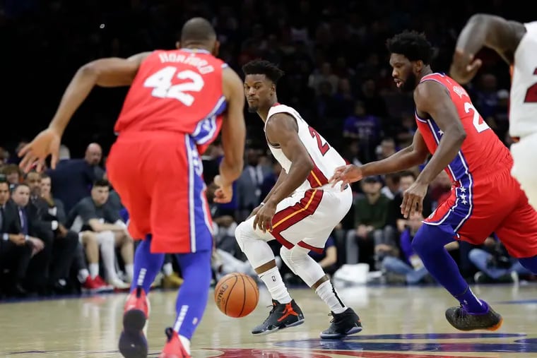 Miami Heat forward Jimmy Butler watches the basketball against Sixers center Joel Embiid and forward Al Horford during the first-quarter on Saturday, November 23, 2019 in Philadelphia.