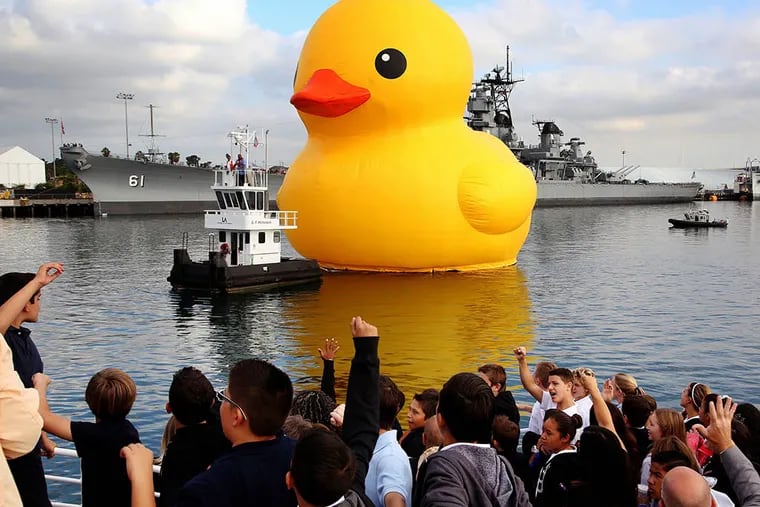 A giant inflatable rubber duck floats past container cranes at the Port of Los Angeles, Ca. on Aug. 20, 2014. (AP Photo / Nick Ut)