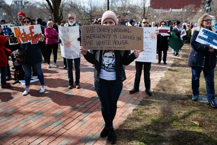 Cat McKay of Alexandria, Va., holds a sign during a protest Monday, Feb. 18, 2019, Lafayette Square near the White House in Washington, to protest that President Donald Trump declared a national emergence along the southern boarder. (AP Photo/Carolyn Kaster)