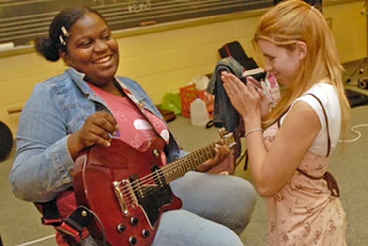 At Girls Rock Philly day camp, Nicole Tyson, 15, of North Wales, applauds Candice Murray, 15, of North Philly.