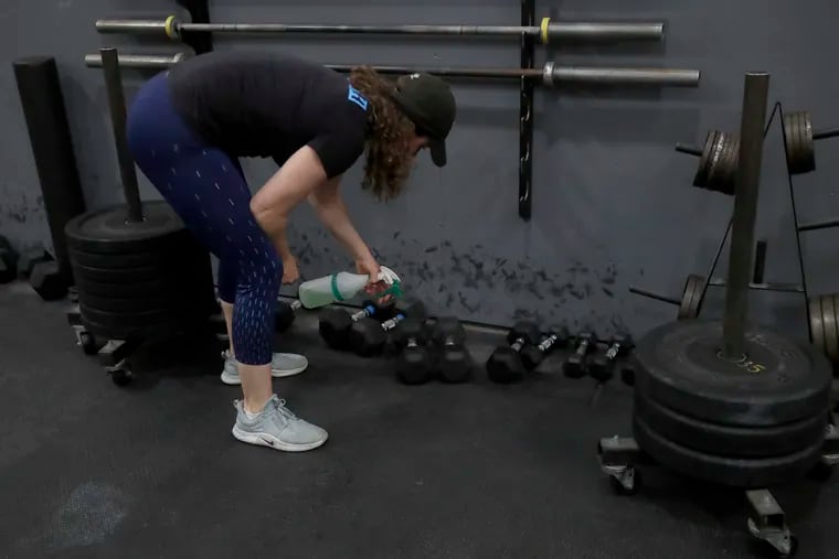 Alexis Garrod, CrossFit Potrero Hill partner and head coach, cleans off weight training equipment in an empty gym, which closed for shelter in place orders over COVID-19 concerns, in San Francisco.