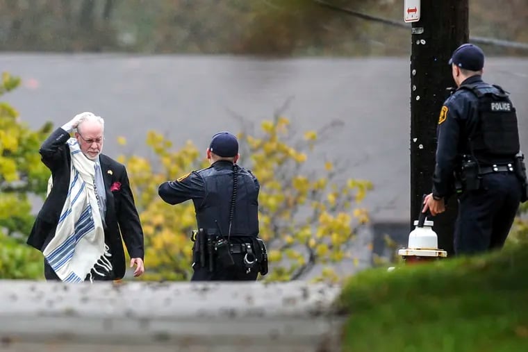 Hazzan Jeffrey Myers, the Rabbi of Tree of Life in PIttsburgh, holds his head as he's escorted by police out of the Tree of Life Congregation synagogue where multiple people were killed Saturday, Oct. 27, 2018, in the Squirrel Hill section of Pittsburgh. (Alexandra Wimley/Pittsburgh Post-Gazette via AP)