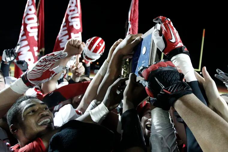 Delsea players all try to touch their championship prize. ( RON CORTES / Staff Photographer )