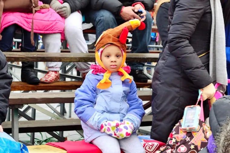 A young spectator waits patiently in the cold on the Ben Franklin Parkway for the Thanksgiving Day Parade to begin. Thursday, November 27, 2014.