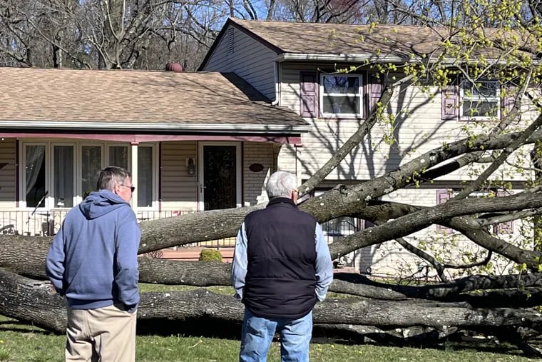 Men survey damage Sunday, April 2, in front of a home on Buttonwood Lane, Cinnaminson, from a suspected tornado that struck April 1, 2023.
