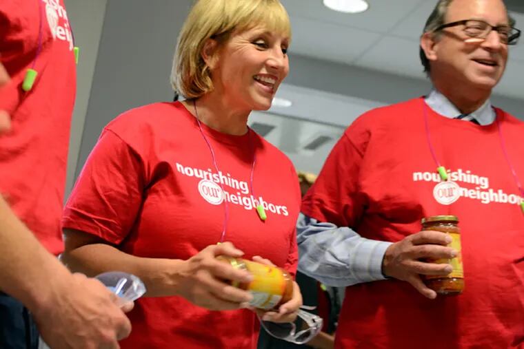 Secretary of Agriculture Doug Fisher (right) joins Acting Governor Kim Guadagno at Campbell's Soup in Camden, Aug. 7, 2014, in preparing jars of Just Peachy Salsa to benefit the Food Bank of South Jersey. (TOM GRALISH/Staff Photographer)