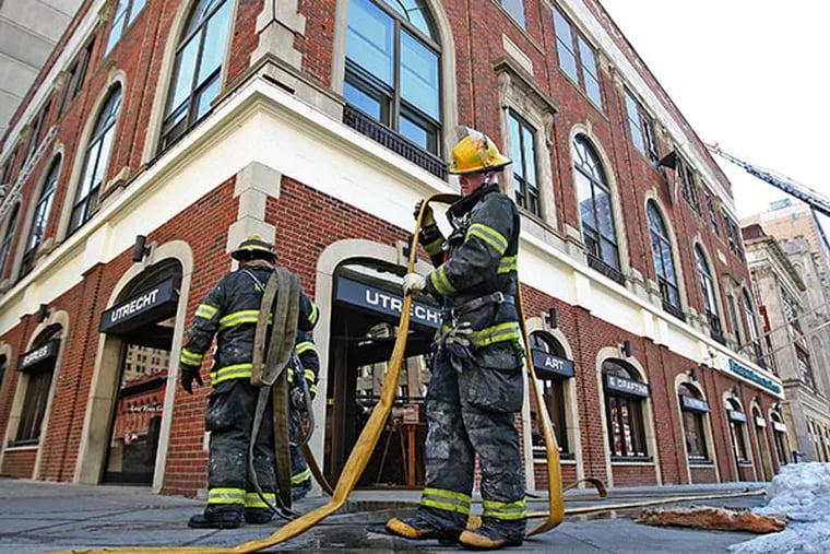 File photo - Philadelphia Firefighter Dan Monaghan of Ladder 23 starts picking up fire hoses after he and other firecompanies put out the blaze at Broad and Spruce. Carl Dranoff says he's got a plan to build what others say is a 40-story tower for a hotel and apartments on South Broad Street.   ( Michael Bryant / Staff Photographer )