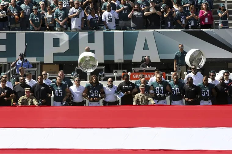 Philadelphia Eagles players and personnel stand during the national anthem before an NFL football game against the New York Giants.