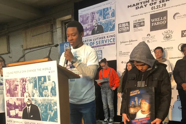 Angel Bermudez, 13, stands on a stage at Girard College on Martin Luther King Jr. Day while listening to Keshan Allen read an essay Bermudez wrote about losing his father to gun violence.