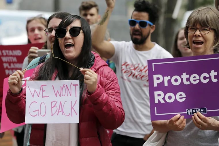 FILE – In this July 10, 2018, file photo, Hillary Namba, left, of Seattle, holds a wire coat hanger and a sign that reads "We Won't Go Back," as she takes part in a protest in Seattle against President Donald Trump and his choice of federal appeals Judge Brett Kavanaugh as his second nominee to the Supreme Court. If a Supreme Court majority shaped by President Donald Trump overturns or weakens the right to abortion, the fight over its legalization could return to the states. (AP Photo/Ted S. Warren, File)