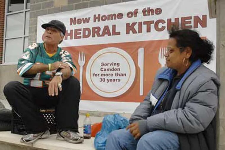Michael Delgado, left, and Floret Santiago sit in front of the Cathedral Kitchen waiting for its 4:00 p.m. opening. (Jonathan Wilson / Staff Photographer)