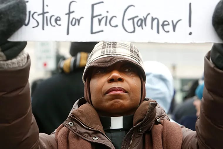 Betty J. Tom sheds a tear while participating in a demonstration against grand jury decisions not to indict police officers involved in the chokehold death of Eric Garner in New York City and the fatal shooting of Michael Brown in Ferguson, Missouri, Friday, Dec. 5, 2014 in White Plains, N.Y.