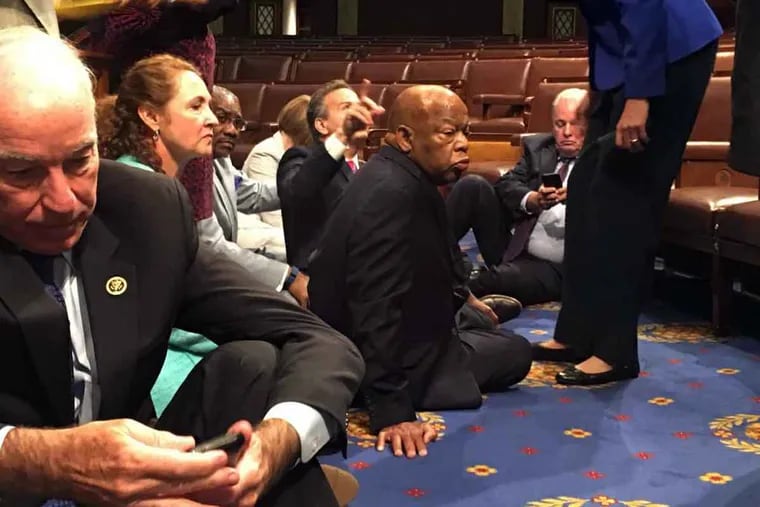 Democratic members of Congress, including Rep. John Lewis, D-Ga., center, and Rep. Joe Courtney, D-Conn., left, participate in a sit-down protest Wednesday, June 22, 2016, on the floor of the House on Capitol Hill in Washington.