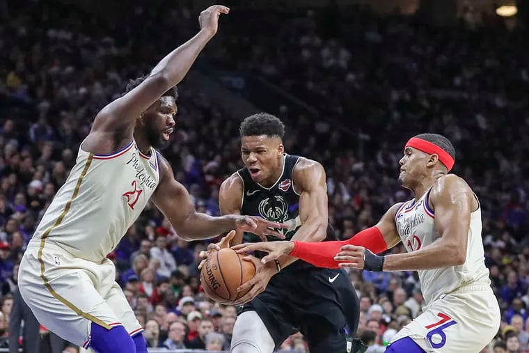 Giannis Antetokounmpo driving to the basket against Joel Embiid and Tobias Harris in the Christmas Day game in 2019.