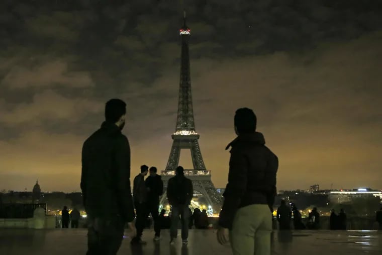 People gather at Trocadero plaza as the lights of the Eiffel tower falls dark at midnight in Paris, France, Wednesday, April 5, 2017.  (AP Photo/Michel Euler)