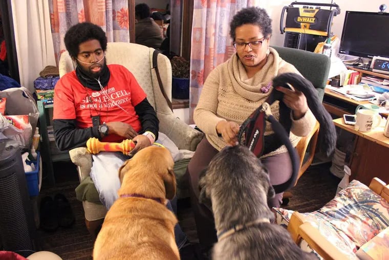 Marqus and Francesca Valentine sit in their living room in Lisle, Ill. They are training their two dogs to be service animals to help Marqus with his disabilities caused by sickle cell disease.