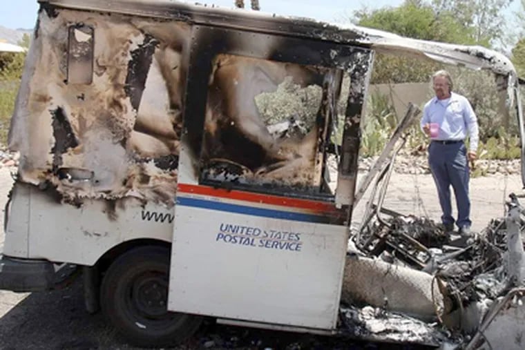 Mailman Brad Yonan surveys hispostal vehicle after it caught fire on his route north of Tucson, Ariz. DAVID SAUNDERS / Arizona Republic