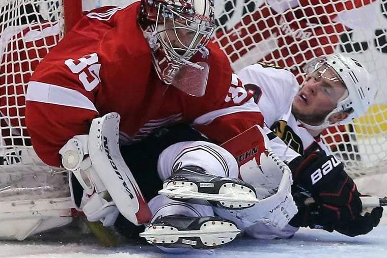 Detroit's Jimmy Howard keeps the puck out of the net as Chicago's Jonathan Toews slides into him. The Red Wings won, 2-0, to take a three-games-to-one lead.