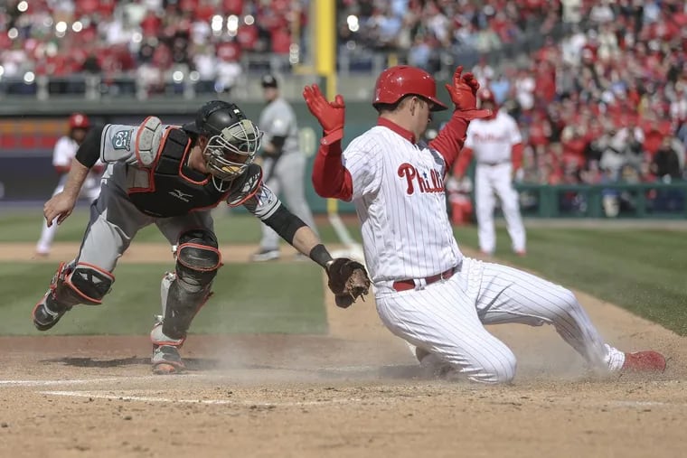 Phillies’ leftfielder Rhys Hoskins scores past Marlins’ catcher Bryan Holaday on a Maikel Franco two-run double during the second inning of the Phillies home-opening win.