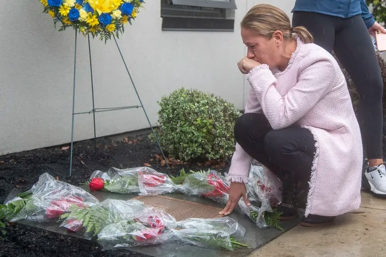 Terri O’Connor kneels down and cries near the plaque dedicated to her late husband, Sgt. James O’Connor IV, during a ceremony at the Fraternal Order of Police Lodge 5 on Friday.