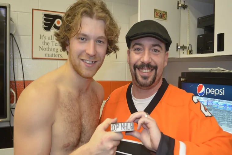 Flyers captain Claude Giroux poses with Philadelphia Police Officer Ed Davies, who was shot in the line of duty on Aug. 13, and the puck Giroux used to score his 100th NHL goal.