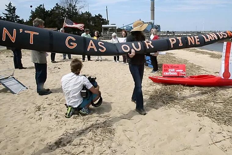 Members of the Sierra Club and other environmental groups hold banners during an Earth Day rally on the beach in Beesleys Point in Upper Township, N.J., Tuesday, April 22, 2014, to protest the proposed pipeline through the Pinelands and continued pollution from the BL England power plant, seen in background. (AP Photo/The Press of Atlantic City, Dale Gerhard)