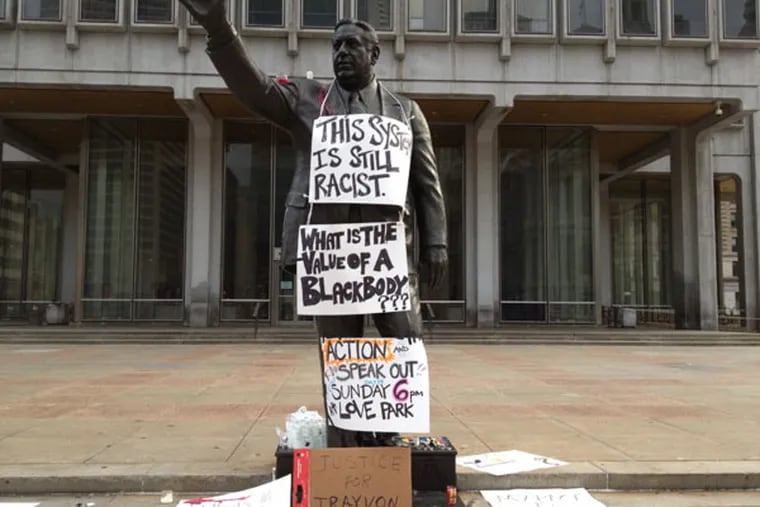 A statue of former Philadelphia Mayor Frank Rizzo in front of the Municipal Services Building on John F. Kennedy Boulevard across from City Hall was decorated with signs protesting the acquittal of George Zimmerman in the fatal shooting of Trayvon Martin.