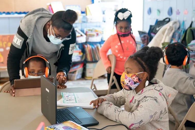 (Left to Right) Dymere, seated with headphones, receives help from lead teacher Rhakiya Hall, as Ocean pulls up a chair to do her schoolwork and Laila, front right, engages in a Zoom session with her music class at the Paulsboro Boys & Girls Club in Paulsboro, NJ, on Oct, 2, 2020. In Paulsboro, about 25 students come to the Boys and Girls center from 8 a.m. to 5 p.m. to do their school work remotely. About 10 or so don’t have Chromebooks so they share devices to attend classes and work independently.