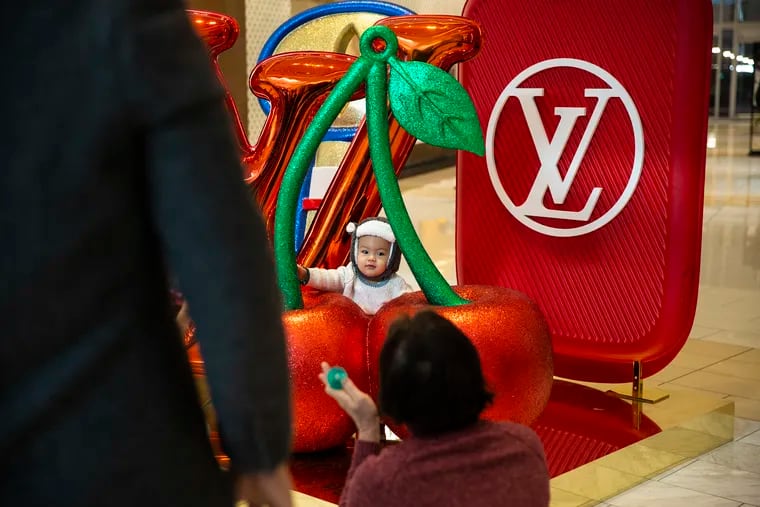 Justin Sok, 1, has his photo taken by family members outside of the Louis Vuitton store in the King of Prussia Mall on the day after Christmas. The National Retail Federation called the week after Christmas "an attractive time" for bargains.