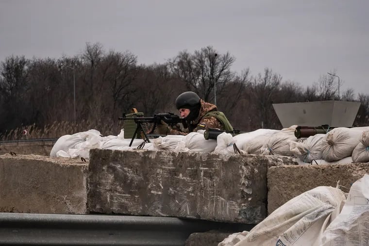 A Ukrainian soldier gets into position as vehicles approach a checkpoint near the city of Dnipro, Ukraine.