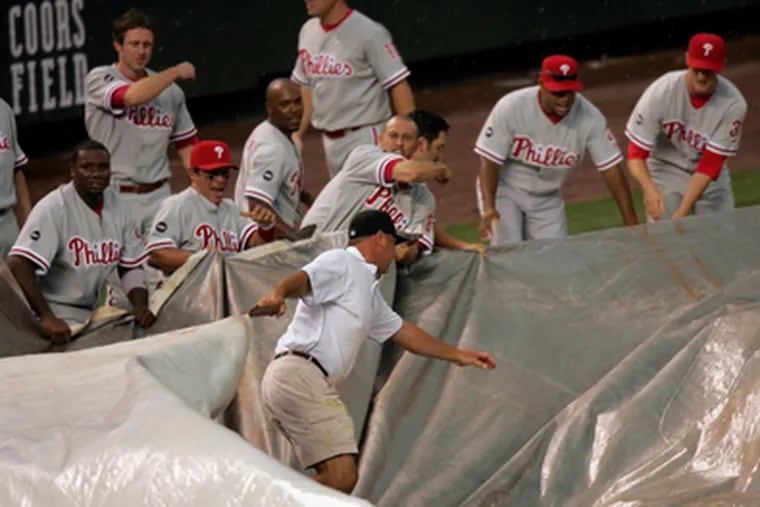 More rain-delay memories: The Phillies helping hold down the wind-blown tarp during a game in Colorado on July 8 of last year.