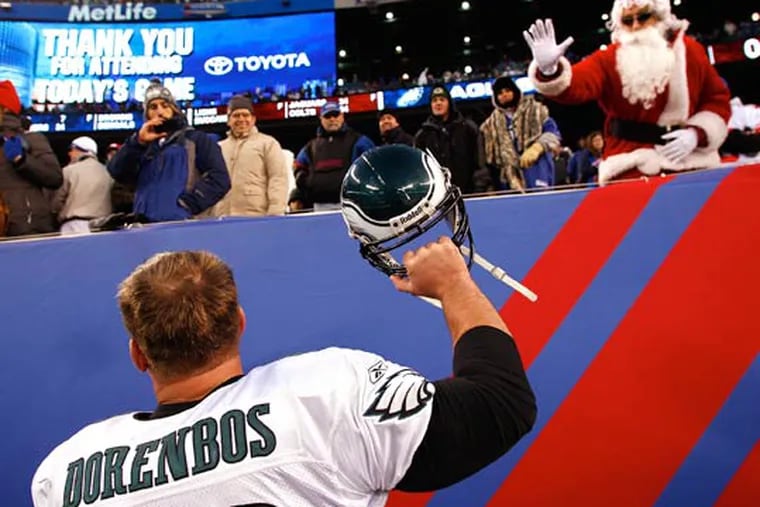 A fan dressed as Santa waves to Jon Dorenbos, left, as he celebrates the Eagles win over the New York Giants. (David Maialetti/Staff Photographer)