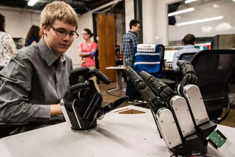Kenneth Chaney , a computer engineering student from Drexel, considers two spare robotic hands at the Lockheed lab. Penn is among the colleges in the contest.