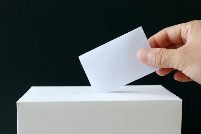 The hand of a woman putting a ballot in the ballot box. Close-up image of ballot and the ballot box.