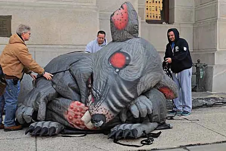 Union members (no ids) deflate one of their giant rat following a rally at City Hall March 13, 2013, to show union displeasure with Mayor Nutter. Attending were labor leaders and rank and file union members representing District Council 33, District Council 47, Firefighters Local 22, the Philadelphia Building Trades, the Philadelphia Federation of Teachers, and the Utility Workers Union of America and others. ( TOM GRALISH / Staff Photographer )