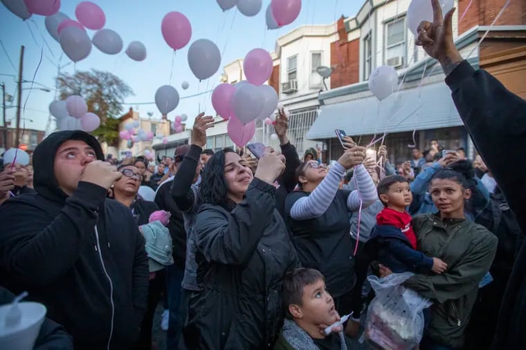 In a file photo, Joan Ortiz, center, the mother of slain 2-year-old Nikolette Rivera, uses her phone to capture the moment that pink and white balloons were released as a tribute to her daughter at a candlelight vigil on Oct. 21, 2019.