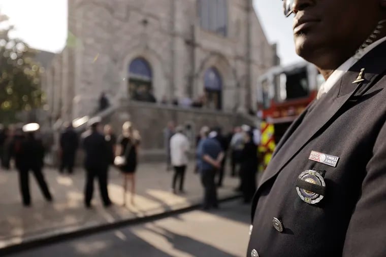 A Philadelphia firefighter, his badge covered with a black ribbon, stands outside Epiphany of Our Lord Church Sunday where a viewing was held for Lt. Sean Williamson, a 27-veteran who was killed June 18 when a fire-damaged building collapsed on him in the city's Fairhill neighborhood.