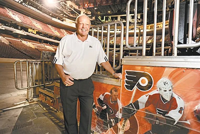 Former Flyer Bob Kelly stands on ice level at the Wells Fargo Center next to photos of himself (closest to his leg) and teammate Bernie Parent during their playing days. (Clem Murray / Staff Photographer)