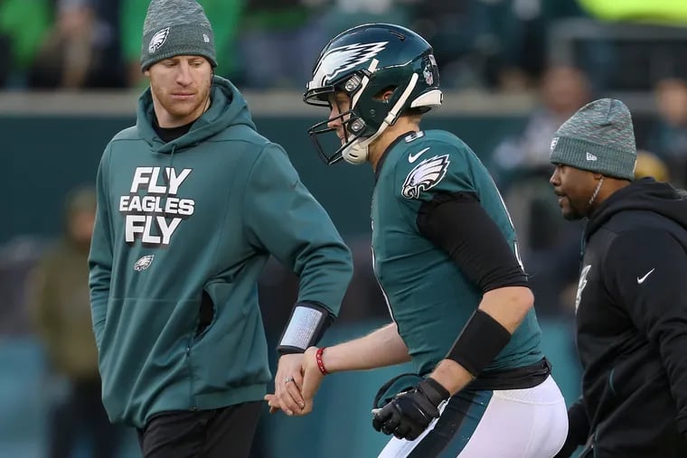 Injured Eagles quarterback Carson Wentz, left, helping quarterback Nick Foles up after he took a hard hit in the fourth quarter against the Texans on Dec. 23.