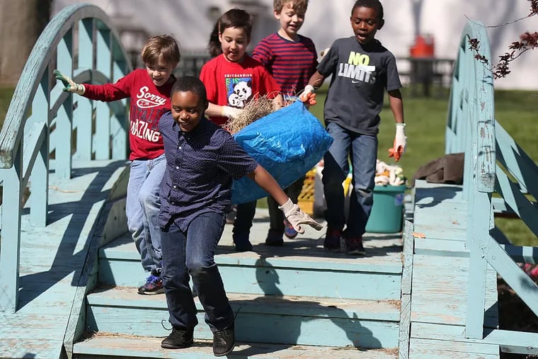 Third graders (from left) Oliver Peterson, Brandon Green, Kieran O’Donnell, Luc Bastien, and Marcellus Jeter carry a bag of dead grass away during the creek-side project on the grounds of Abington Friends.