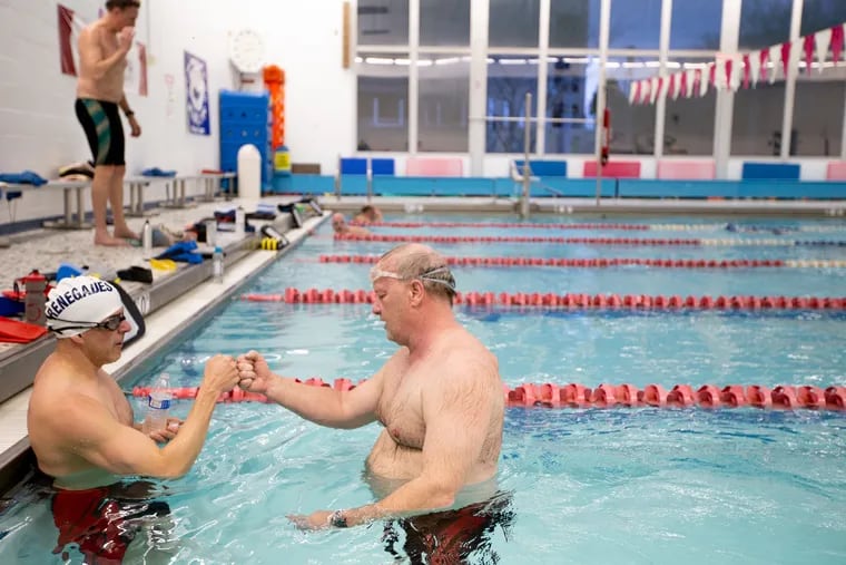 John Rosania (left) fist bumps Dave Scott after their Masters swim team practice at the pool at Rowan College's Pemberton campus. The pool is set to be shut down in August and some community members are fighting to save it.